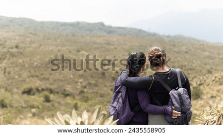 Two friends share a moment overlooking a mountainous landscape, deep in conversation and connection