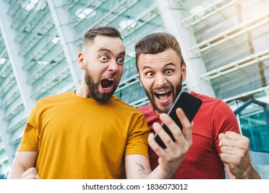 Two friends showing sincere emotions of joy about victory in online lottery. Men being happy winning a bet in online sport gambling application with football stadium on the background. - Shutterstock ID 1836073012