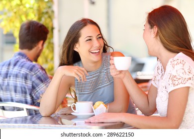 Two friends or sisters talking taking a conversation in a coffee shop terrace looking each other - Powered by Shutterstock