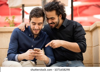 Two Friends Sitting And Looking At The Phone Together.