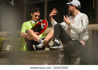 Two friends are sitting on the wall and talking while smiling at each other