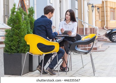 Two friends sitting outdoor in cafe thinking, looking at tablet and discussing their business. - Powered by Shutterstock