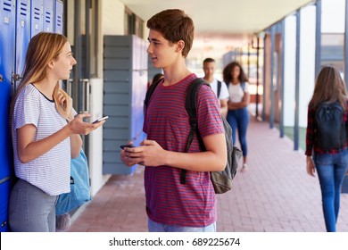 Two friends with smartphones talking in school corridor - Powered by Shutterstock