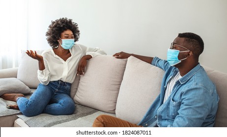 Two  Friends In Social Distancing Sitting On Sofa. Best Friends Having Coffe Together While Separated By Social Distancing On Sofa At Home. Preventing Covid 19 Coronavirus Pandemic Infection Spread.