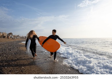 Two friends surfers going for surfing in the sea. Carrying surfboards running in to the sea surfing - Powered by Shutterstock