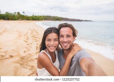 Two Friends Taking Self Portrait Picture With Phone. Smiling Young Interracial Couple Taking Selfie On Vacation Travel. Asian Woman, Caucasian Man. Two Young Adults Happy.