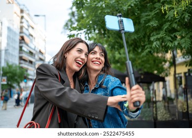 Two Friends Taking a Selfie with a Selfie Stick Outdoors