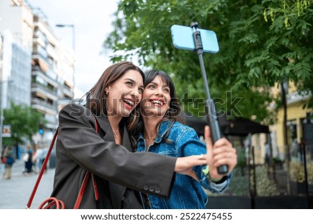 Two Friends Taking a Selfie with a Selfie Stick Outdoors