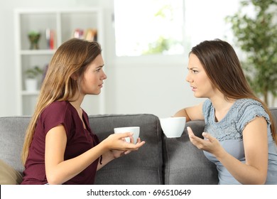 Two Friends Talking Seriously Sitting On A Couch At Home