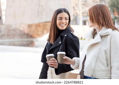 Two friends talking while drinking a take away coffee in the street