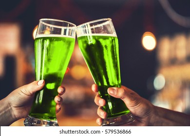 Zwei Freunde toasteln mit einer Brille grünes Bier in der Kneipe mit freiem Platz für Ihren Text. Schöner Hintergrund des Oktoberfestes und des St. Patrick's Day. feines Korn. Weicher Fokus. SCHLECHTER DOF
