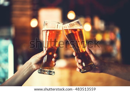 Two friends toasting with glasses of light beer at the pub. Beautiful background of the Oktoberfest. fine grain. Soft focus. Shallow DOF