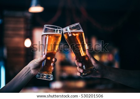 Two friends toasting with glasses of light beer at the pub. Beautiful background of the Oktoberfest. fine grain. Soft focus. Shallow DOF.