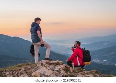 Two friends tourists photographers are relaxing while drinking a cup of coffee during the hike on the mountain top adventure travel.