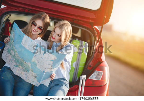 two\
friends travel concept with map sitting in\
car