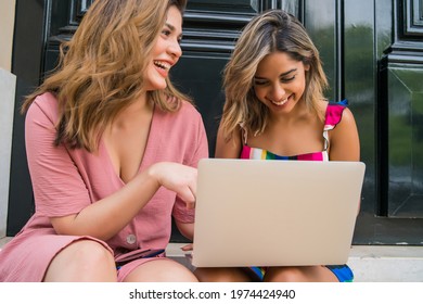 Two Friends Using Laptop Outdoors.