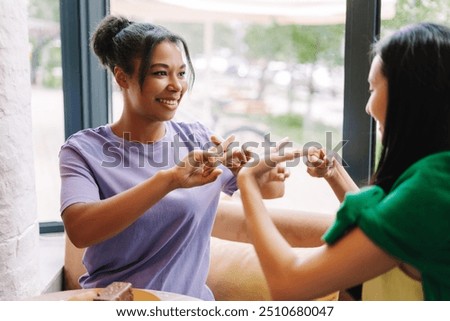 Two friends are using sign language while having a pleasant conversation in a cafe, enjoying each other's company over coffee and cake. Inclusion concept