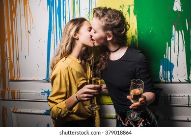 two friends at the wall with champagne in a nightclub kiss, unconventional relationships, lesbian