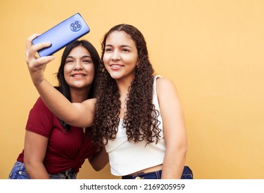 Two Friends Women With Brackets Taking A Photo Over Yellow Background.