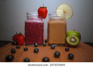 Two fruit smoothies side by side with an array of fruit scattered around