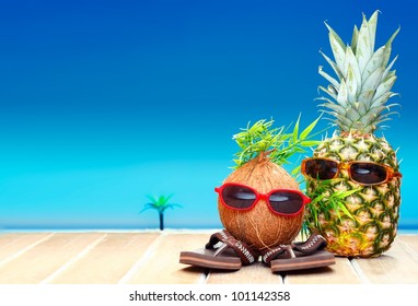 Two fruity friends, a coconut and pineapple, with fun foliage haistyles and trendy sunglasses in tropical paradise