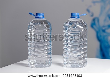 Two full 5 liter bottles of water on a white table on a gray background. Water delivery