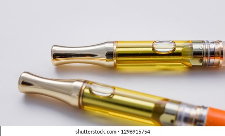 Two full grams concentrated THC/CBD oil in glass cartridges for vaping isolated on white background.