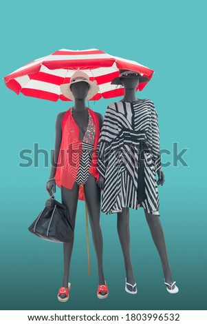 Two full length female mannequins dressed in fashion beachwear, isolated on blue background. No brand names or copyright objects.