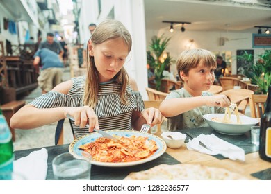 Two Funny Kids Having Lunch In The Restaurant, Eating Ravioli And Pasta