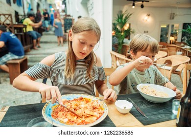 Two Funny Kids Having Lunch In The Restaurant, Eating Ravioli And Pasta