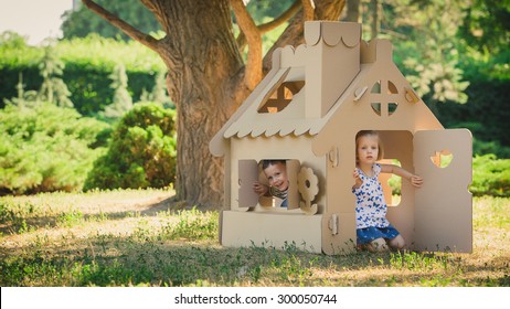 Zwei lustige Kinder spielen in einem Spielzeughaus aus Pappe. An einem Sommertag im Park