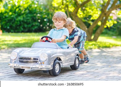 Two funny little friends playing with big old toy car in summer garden, outdoors. Active leisure with kids on warm summer day. - Powered by Shutterstock