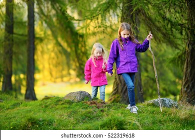 Two funny little sisters having fun during forest hike on beautiful autumn day in Italian Alps