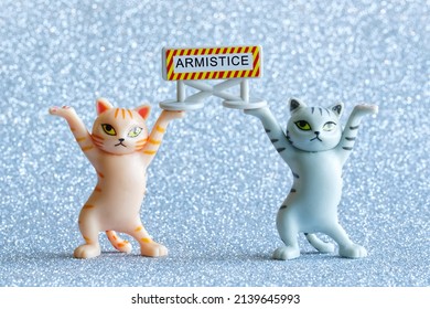 Two funny toy kittens are holding a sign that says armistice. Silver background. Close-up