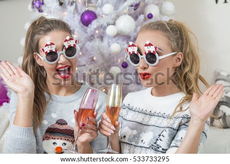 two funny women drinking champagne in decorated for Christmas room