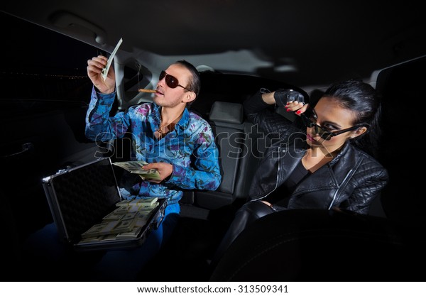 Two gangsters with\
dollars in the car