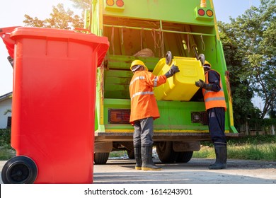 Two garbage men working together on emptying dustbins for trash removal with truck loading waste and trash bin.