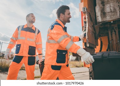 Two garbagemen working together on emptying dustbins for trash removal