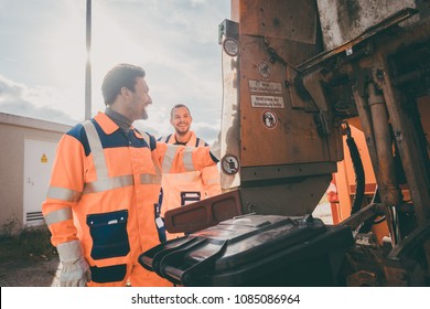 Two Garbagemen Working Together On Emptying Dustbins For Trash Removal