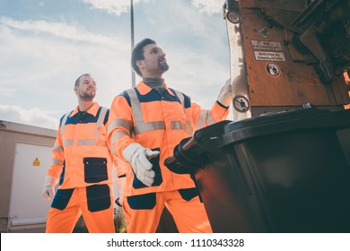 Two Garbagemen Working Together On Emptying Dustbins For Trash Removal