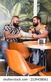 Two Gay Men Planning Their Vacation Inside A Cocktail Bar.