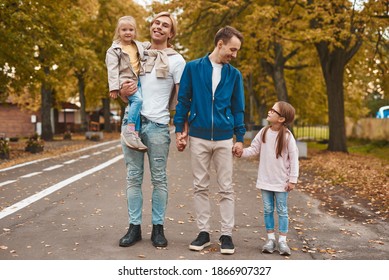 Two Gay Parents With Their Adopted Daughters Walking In Park Together. Happy LGBT Family Concept.