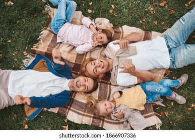 Two gay parents with their adopted daughters having fun together while lying on blanket in park. Happy LGBT family concept.