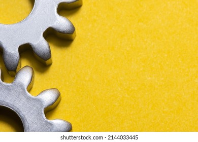 two gears geared on a yellow background with copy space, geared steel sprockets, sprocket, background with gearing parts, horizontal