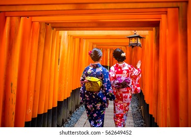 Two geishas wearing traditional japanese kimono among red wooden Tori Gate at Fushimi Inari Shrine in Kyoto, Japan. Fushimi Inari Shrine one of famous landmarks. - Powered by Shutterstock