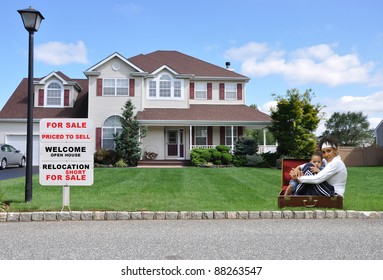 Two Generation Family Grandmother Grandson In Suitcase On Front Yard Lawn Next To Realtor Relocation For Sale Sign