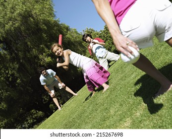 Two Generation Family Playing Softball In Park, Girl (6-8) Batting, Smiling (tilt)