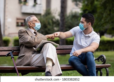 Two Generations, Grandfather And Grandson Talking With Covid Masks In The Park