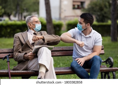 Two Generations, Grandfather And Grandson Talking With Covid Masks In The Park