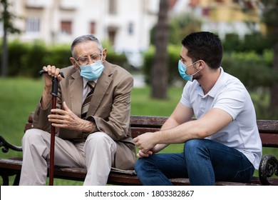 Two Generations, Grandfather And Grandson Talking With Covid Masks In The Park